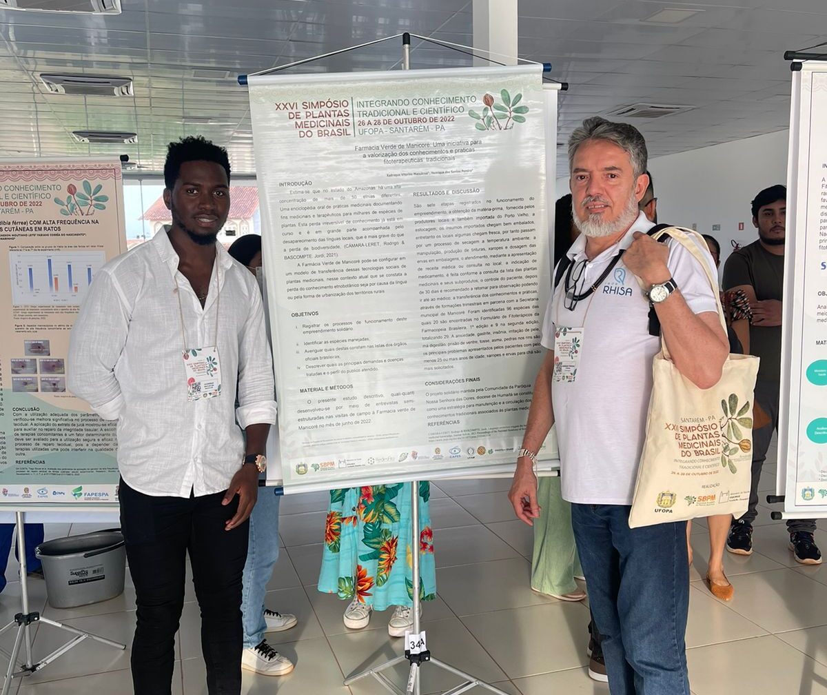 Msc. Xadreque Macuácua (à esq.) e Prof. Dr. Henrique Pereira apresentando o banner "Farmácia Verde de Manicoré: Uma iniciativa para a valorização dos conhecimentos e práticas fitoterapêuticas tradicionais"